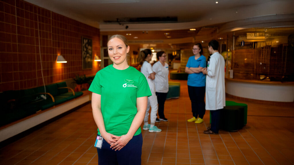 OKKS:n fysioterapeutti ja taustalla muuta henkilökuntaa